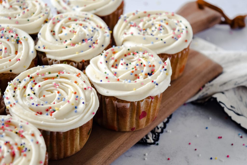 vanilla cupcakes with piped icing and rainbow sprinkles