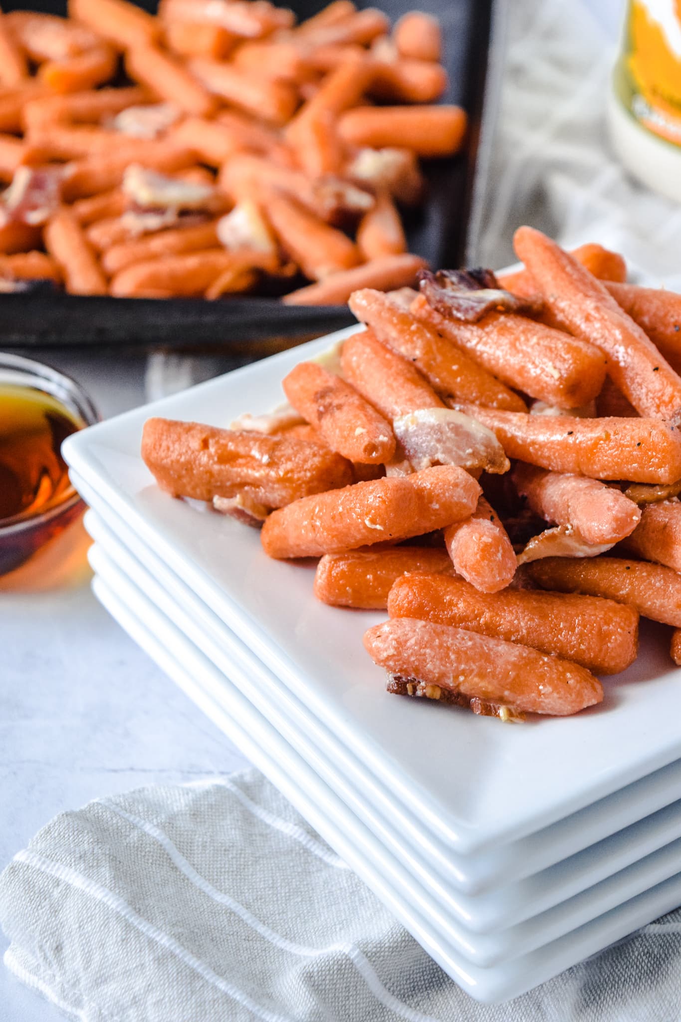 Maple Bacon Roasted Baby Carrots on Stack of White Plates
