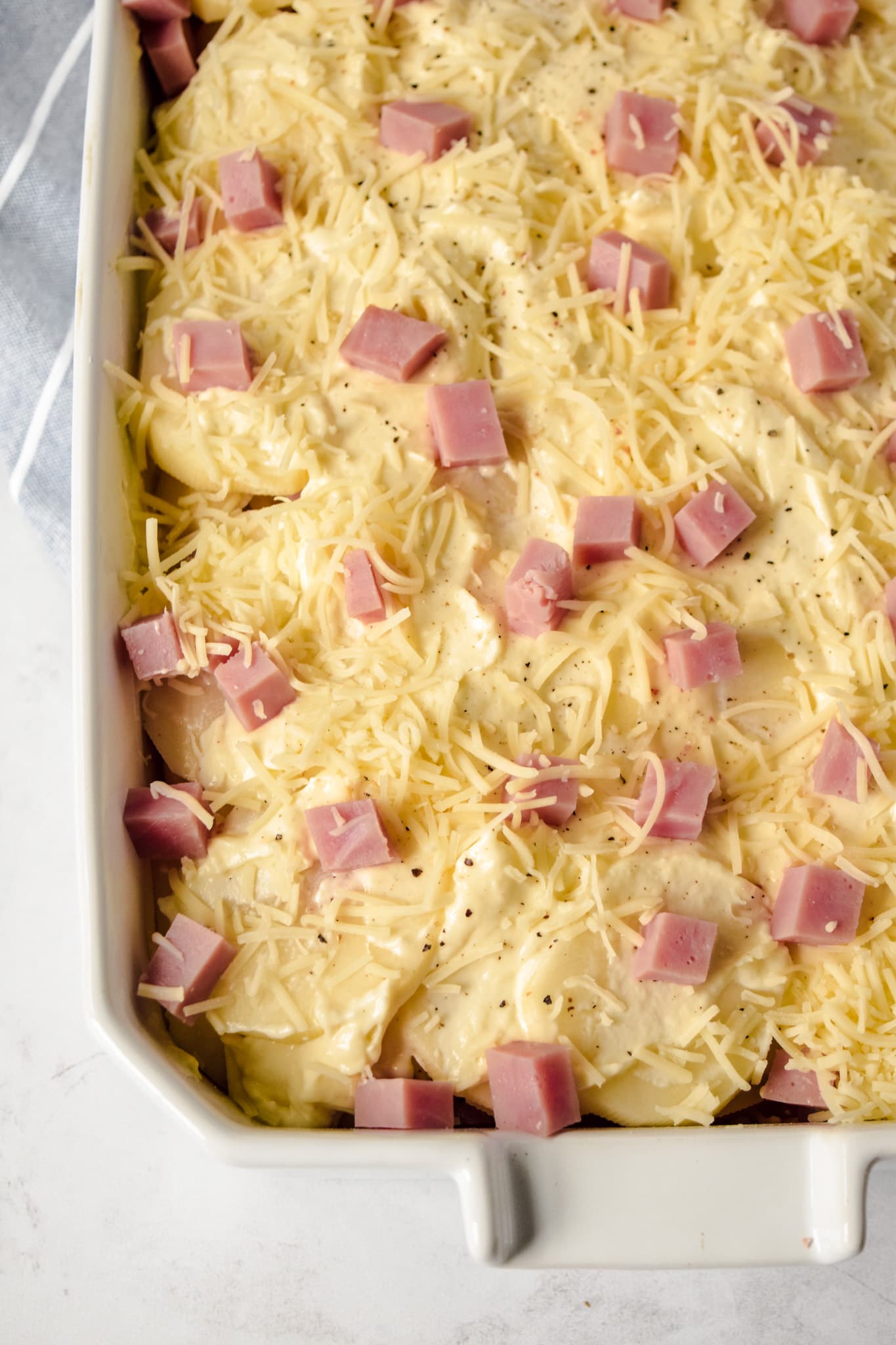 Scalloped potatoes with ham in a white rectangular baking dish