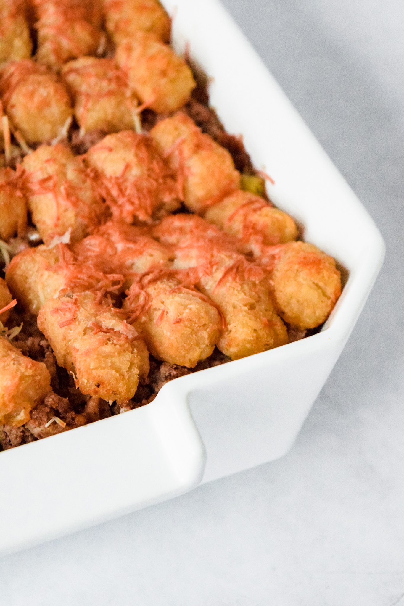 Baked Tater Tot Casserole with Ground Beef and Vegetables in a White Baking Dish