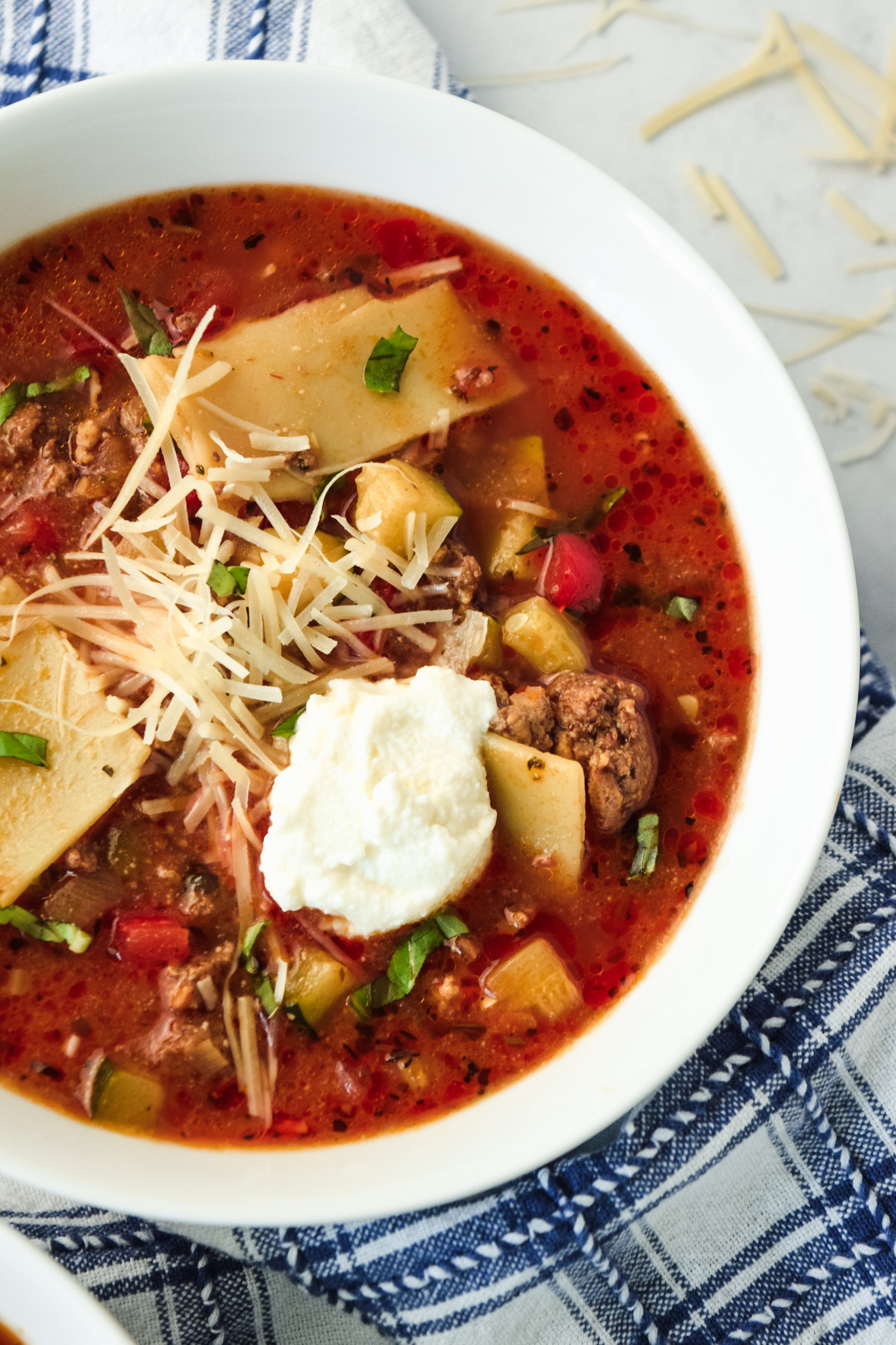 Bowl of gluten free lasagna soup with a dollop of ricotta