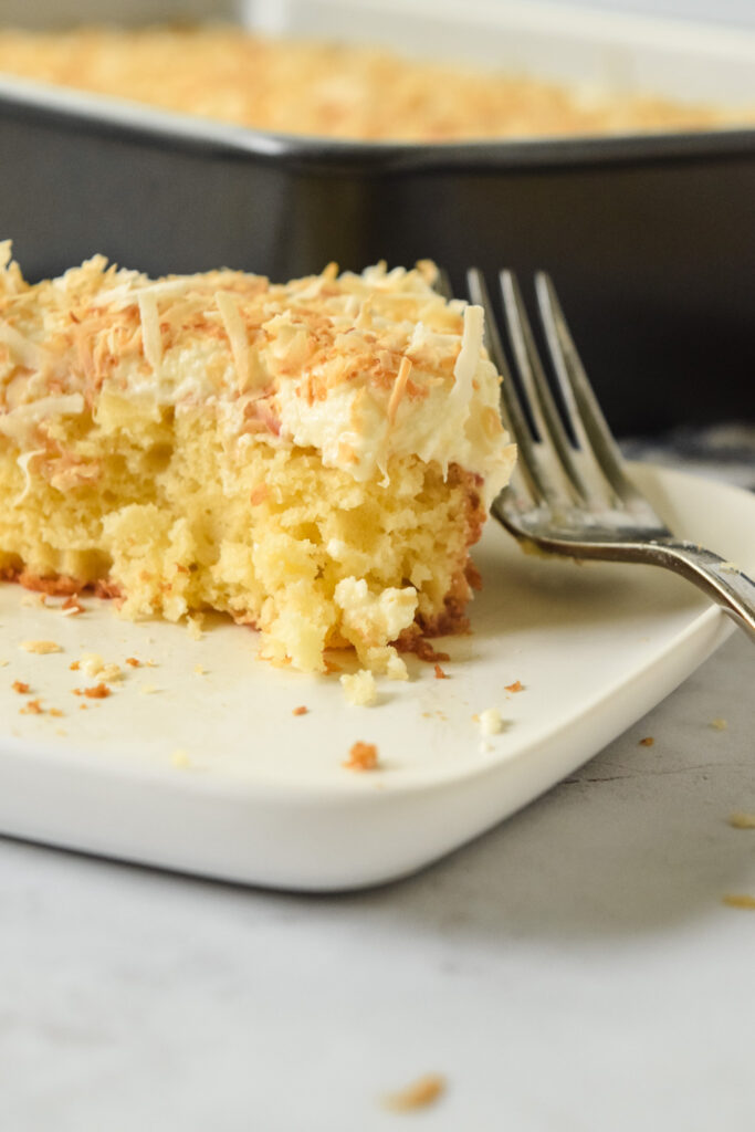 Slice of Gluten Free Pina Colada Cake with Toasted Coconut Flakes