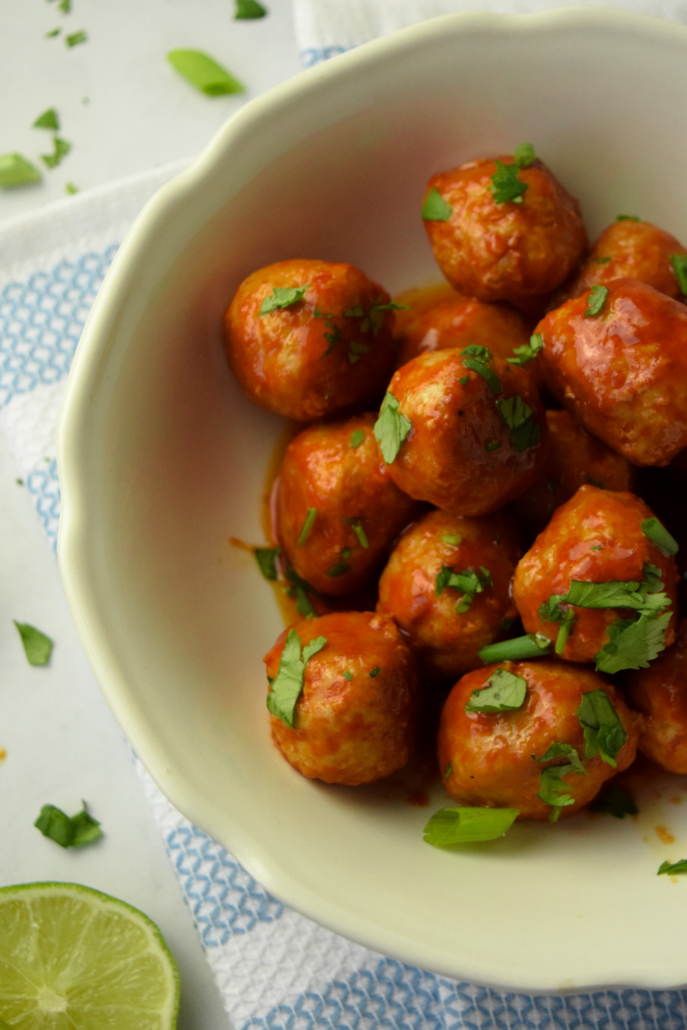 Buffalo chicken meatballs in a white bowl garnished with cilantro
