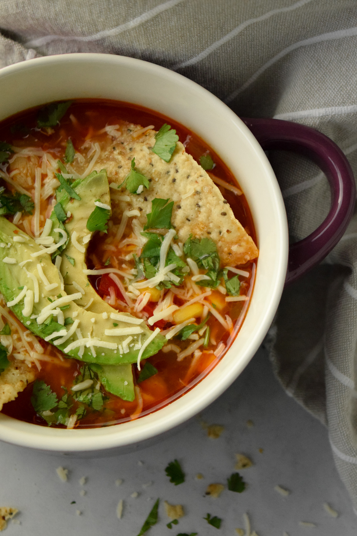 Crock of Chicken Tortilla Soup with Tortilla Chips, Avocado, Cilantro, and Shredded cheese